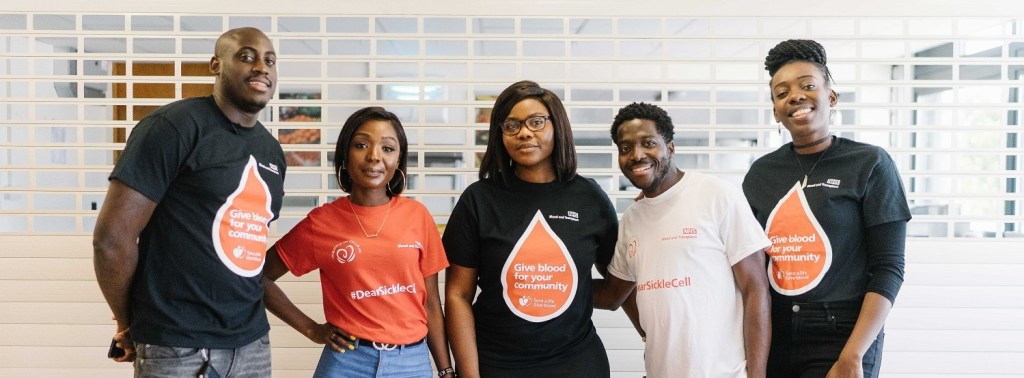 Group of five individuals standing together, wearing t-shirts promoting blood donation and sickle cell awareness.
